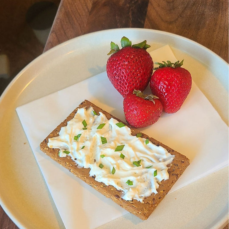 Fello Everything Bagel Bar topped with cream cheese and chives and served with strawberries for breakfast.