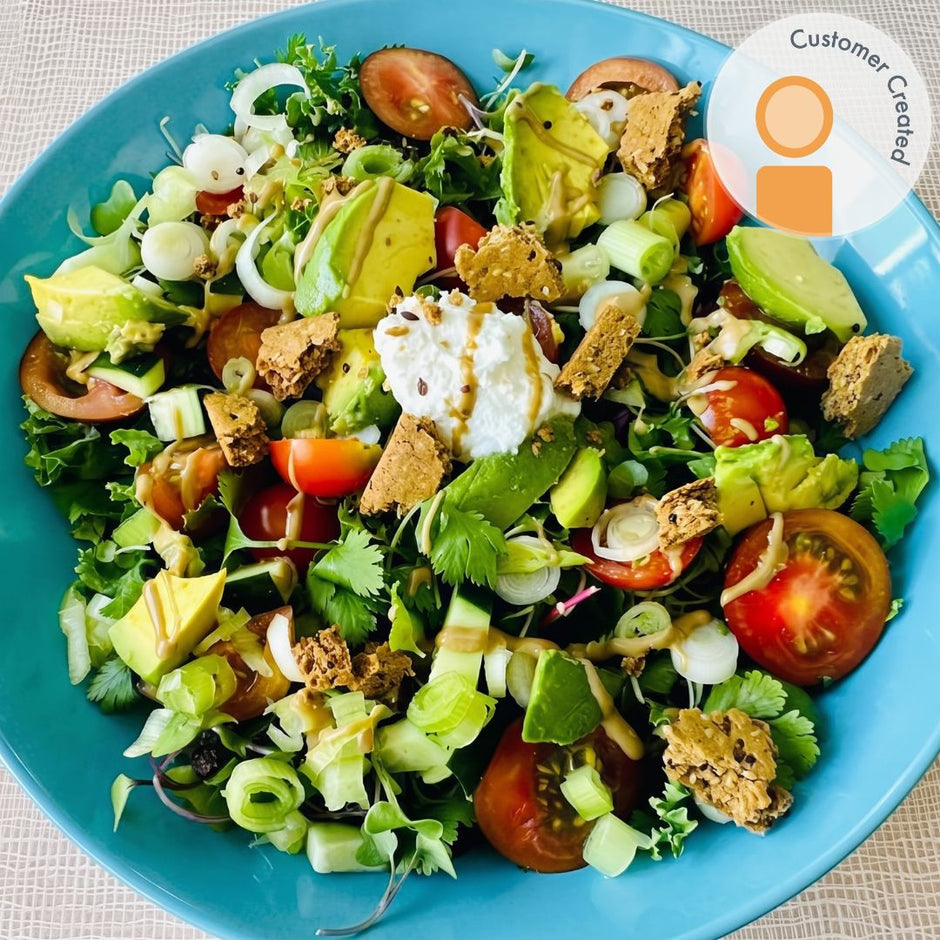 Fello Everything Bagel Protein Bars on top of salad with avocado, goat cheese, tomatoes, and greens.  Fan Recipe.