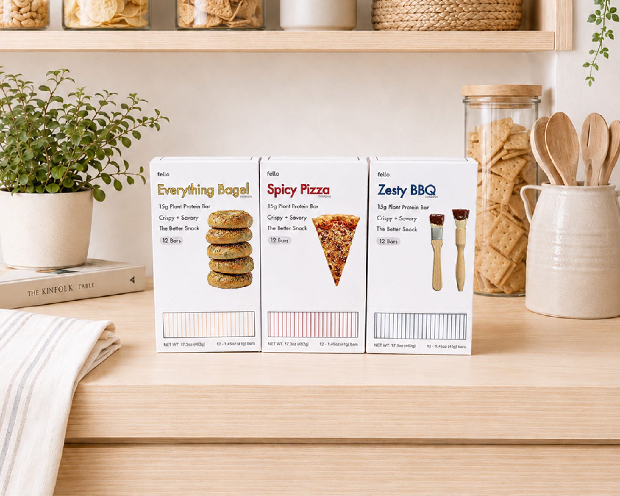 Three boxes of fello savory protein bars in Everything Bagel, Spicy Pizza, and Zesty BBQ flavors on a kitchen counter.