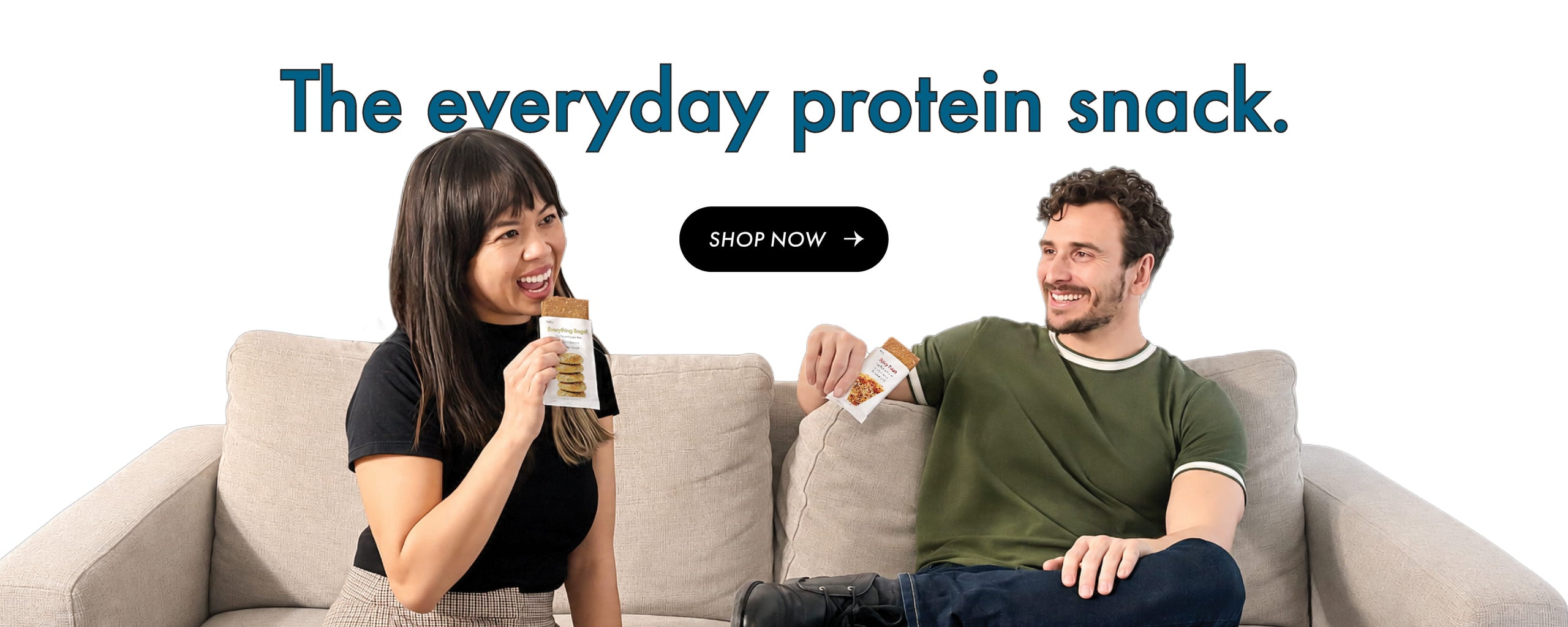 The everyday protein snack. Shop Now. Man and woman smiling on a couch holding protein bars.